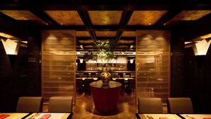 A restaurant with a central round table, wooden flooring, and a ceiling with exposed beams.