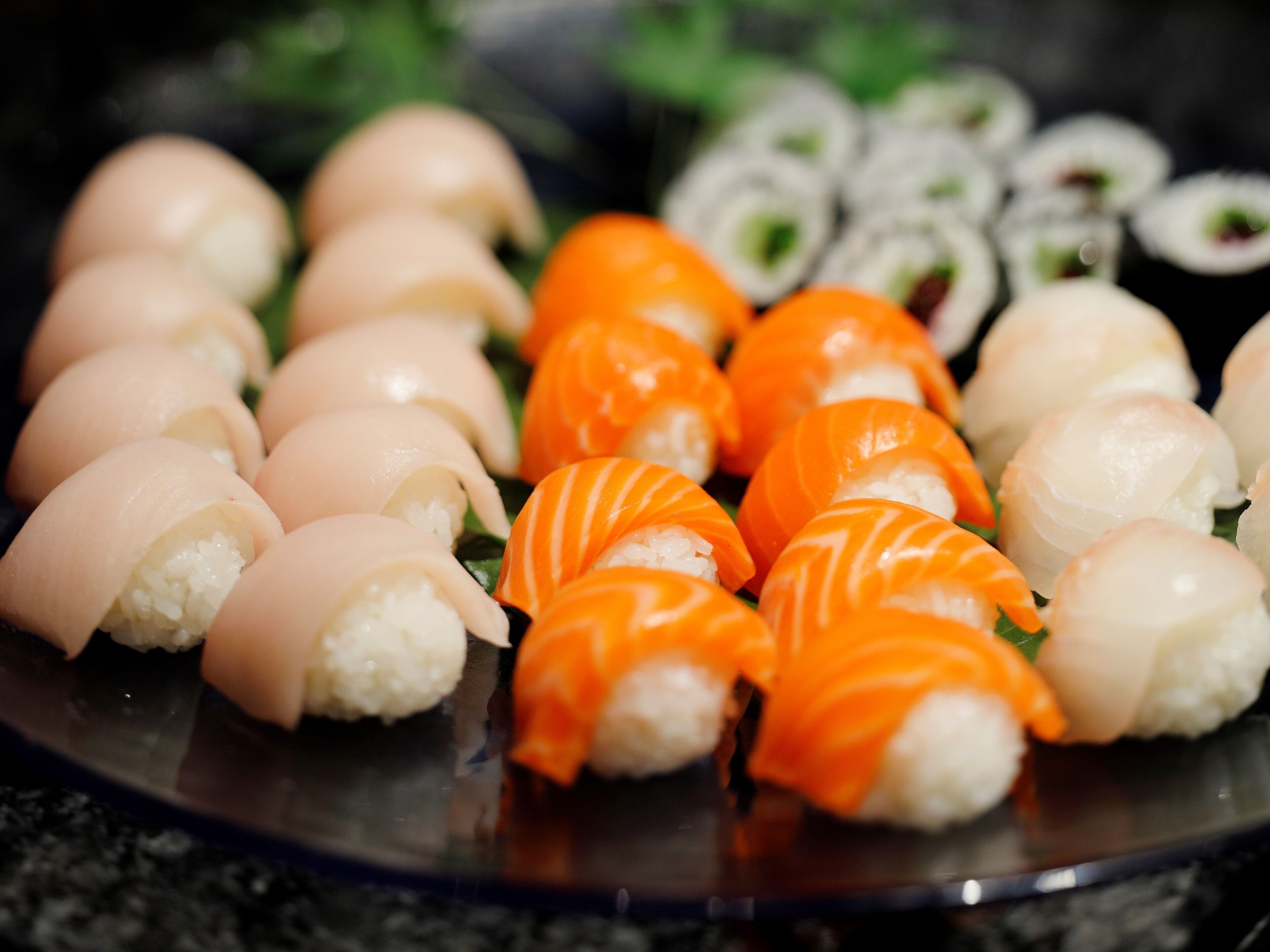 Une assiette de sushis comprenant différents types, notamment des rouleaux au saumon et au poisson blanc.