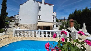 Eine moderne Villa mit Schwimmbad, einer Steinfassade und einem weißen Balkonläufer.