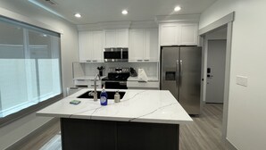 A modern kitchen with white cabinetry, stainless steel appliances, and a marble countertop. - Spacious 3 Bedrooms with 2 King Beds and 2 Bathrooms (Murray)