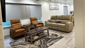 A modern living room with leather sofas, a coffee table, and a large window with blinds. - Spacious 3 Bedrooms with 2 King Beds and 2 Bathrooms (Murray)