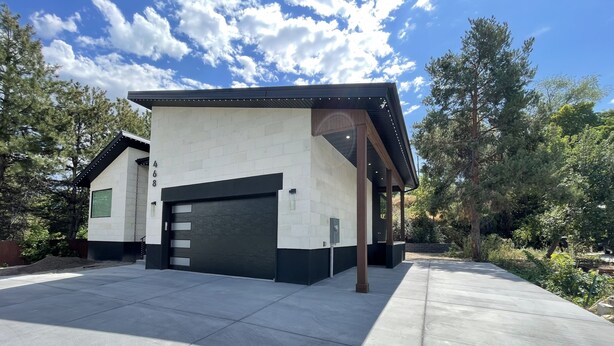 A modern building with a garage, surrounded by trees and a clear sky. - Spacious 3 Bedrooms with 2 King Beds and 2 Bathrooms (Murray)