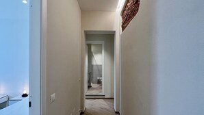 Un passadís estret amb sòl de fusta, parets blanques i una porta que dóna a un bany.