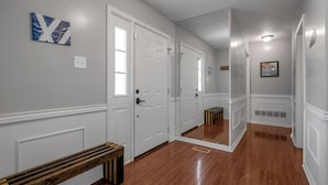 A hallway with white doors, a bench, and a mirror reflecting the space. - Your Kentucky Home (Georgetown)