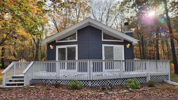 Une cabane à deux étages avec une véranda couverte et une cheminée.