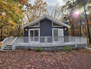Une cabane à deux étages avec une véranda couverte et une cheminée.