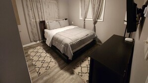 Une chambre à coucher avec un lit, un bureau, un ventilateur de plafond et une fenêtre avec des rideaux.