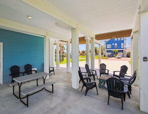 Eine Außenpatio-Terrasse mit Picknicktischen und -stühlen, ein überdachter Bereich mit Holzboden und Blick auf eine Wohnstraße.