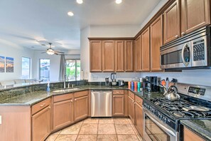 A modern kitchen with wooden cabinets, stainless steel appliances, and a granite countertop.