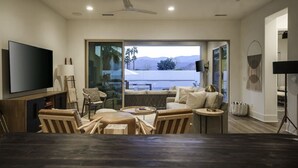 A modern living room with a large flat-screen TV, comfortable seating, a dining table, and a view of mountains through large glass doors. - Good Life La Quinta!  PGA West! Mist/Pool/Spa/Putt (La Quinta)