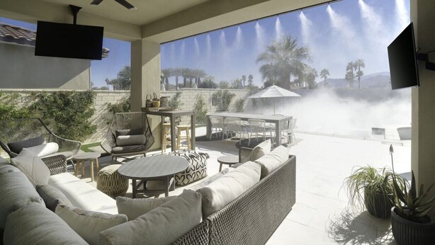 A sunlit patio with wicker furniture, a flat-screen TV, and a view of palm trees and a fountain. - Good Life La Quinta!  PGA West! Mist/Pool/Spa/Putt (La Quinta)