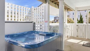 Un jacuzzi con un banco de madera, una valla blanca y un cartel con las normas del spa.