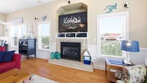 Una sala de estar con chimenea, televisión y vistas al exterior.