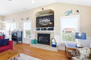 A living room with a fireplace, a television, and a view of the outside.