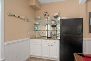 A kitchen with white cabinetry, a black refrigerator, and a glass display shelf with decorative items.