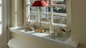 Et værelse med et stort vindue, en rød lampe og et lille bord med pynt.