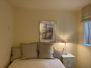 A bedroom with a bed, pillows, a nightstand, a lamp, and a framed picture on the wall. - Haus Wattblick App. 06 - Wattblick (Sylt)