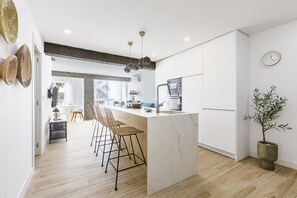Et moderne køkken med en marmorø, barstole, en mikroovn og en potteplante.