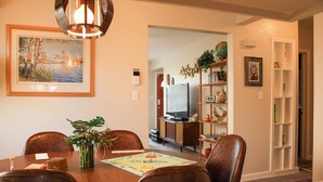 A dining area with a wooden table, chairs, a vase with a plant, and a framed picture on the wall. - Ultra Clean, Private, Comfy Home in Prime Location. Sleeps up to 8. (Milwaukee)