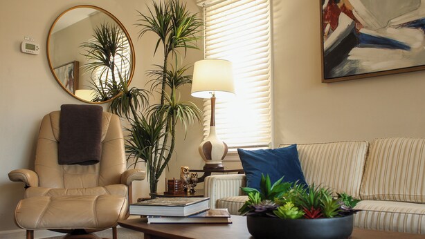 A living room with a beige leather chair, a sofa, a coffee table, a lamp, a mirror, and a painting on the wall. - Ultra Clean, Private, Comfy Home in Prime Location. Sleeps up to 8. (Milwaukee)