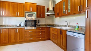 A modern kitchen with wooden cabinets, stainless steel appliances, and a Bosch dishwasher.