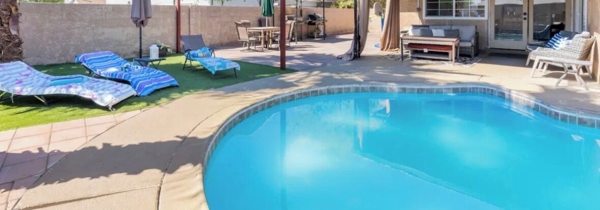 Una piscina con sillas de descanso y un área de terraza.