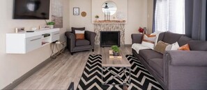 A modern living room with a fireplace, two sofas, a TV, and a white entertainment unit. - Lovely home w pool (Las Vegas)