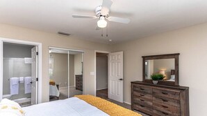 Ein Schlafzimmer mit Bett, Kommode, Spiegel und Deckenventilator.