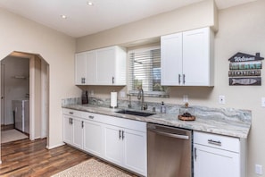 Kitchen features a dishwasher, window with blinds, and a welcome sign.