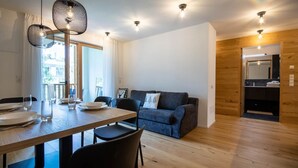 Un salón moderno con suelo de madera, una mesa de comedor preparada para cuatro personas y un sofá azul.