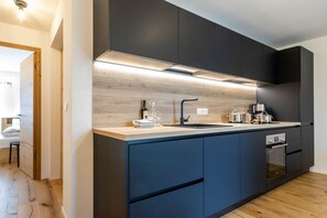 Une cuisine moderne avec des meubles de couleur sombre, un plan de travail en bois et des appareils électroménagers intégrés.