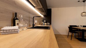 Una cocina moderna con encimera de madera, grifo negro y una botella de vino.