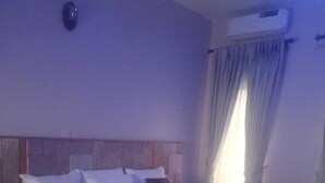Ein Standard-Hotelzimmer mit Bett, Nachttisch und Wandgerät für die Klimaanlage.