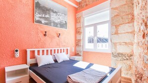 A bedroom with a bed, white nightstands, a window with a view of buildings, and a picture on the wall. - Modern apartment with roof terrace in Athens (Athens)