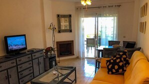 A living room with a sofa, a coffee table, a television, and a fireplace. - Flat Sleeps 4 with Pool and Terrace (mijas costa)