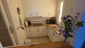 A kitchen with white cabinets, a microwave, a sink, and a wooden countertop. - Flat Sleeps 4 with Pool and Terrace (mijas costa)
