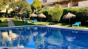 A swimming pool with a clear blue water, surrounded by a well-maintained lawn and a building with balconies. - Flat Sleeps 4 with Pool and Terrace (mijas costa)