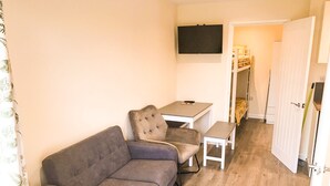 Ein kompakter Wohnraum mit einer Couch, einem kleinen Tisch und einem an der Wand befestigten Fernseher.