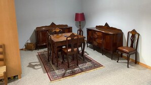 Ein Essbereich mit Holztisch und Stühlen, einem gemusterten Teppich, einer Lampe und einer Kommode.