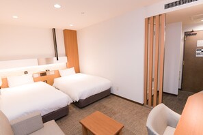 A hotel room with two beds, a wooden headboard, a small table, and a chair. - JR CLEMENT INN HIMEJI (Himeji)