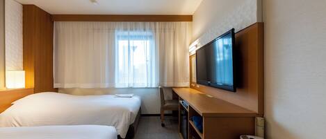 A hotel room with two beds, a desk, a television, and a minibar.
