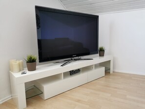 Ein Flachbildfernseher auf einer weißen Unterhaltungsecke mit einer Glasablage darunter.