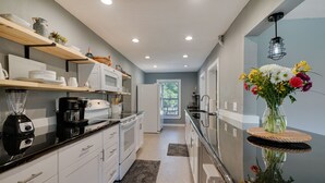 A modern kitchen with white cabinets, a black countertop, and a built-in oven. There is a window with a view of trees, and a vase with flowers on a small table. - Spacious Arcadia Escape Near Public Boat Ramp (Arcadia)