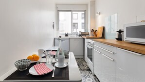 Eine moderne Küche mit weißen Schränken, einer Holz Arbeitsplatte und einer eingebauten Mikrowelle.