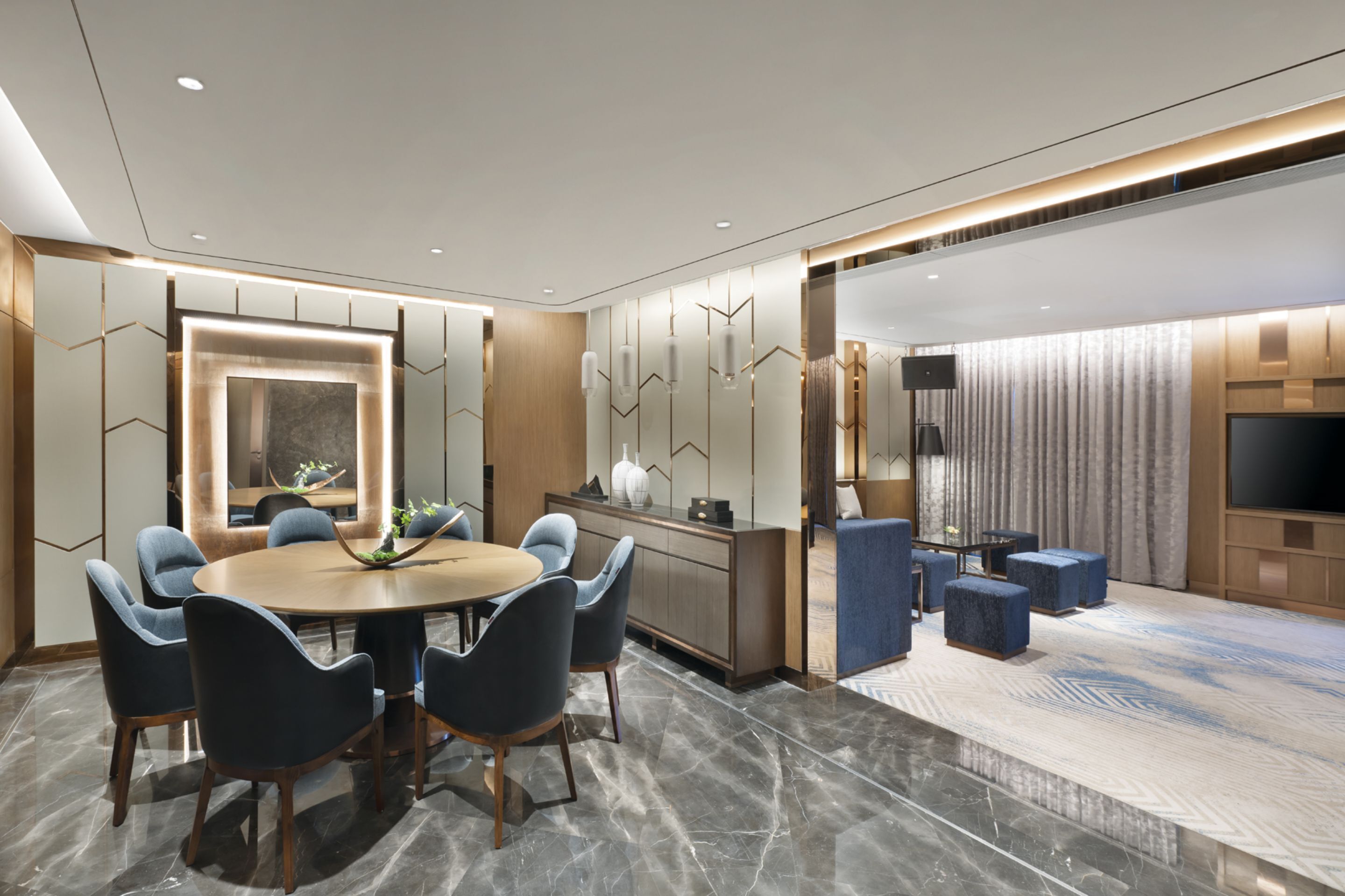 A modern dining area with a round table, blue chairs, and a wooden cabinet.