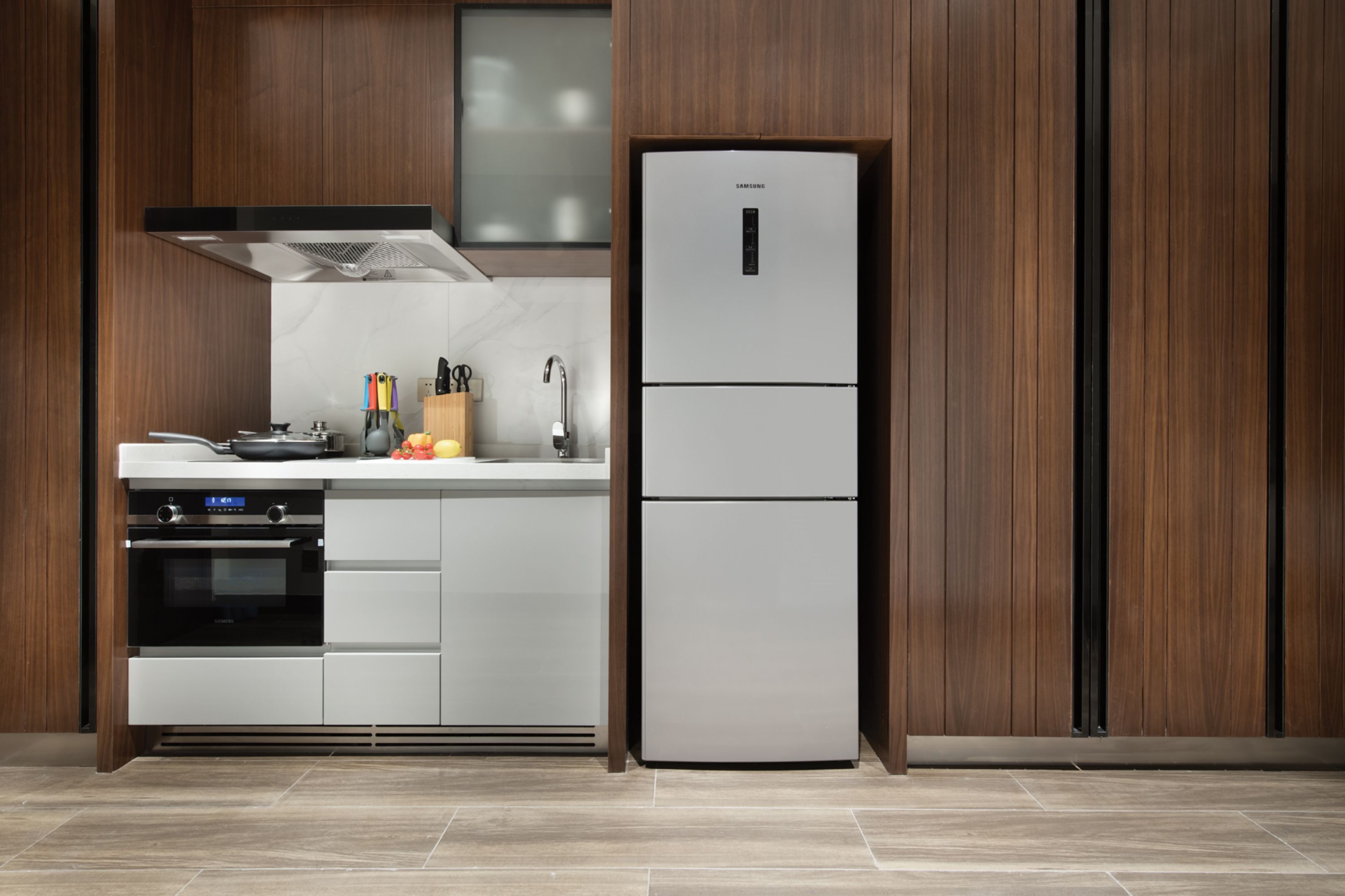 Una cocina moderna con horno empotrado, refrigerador de acero inoxidable y muebles de madera.