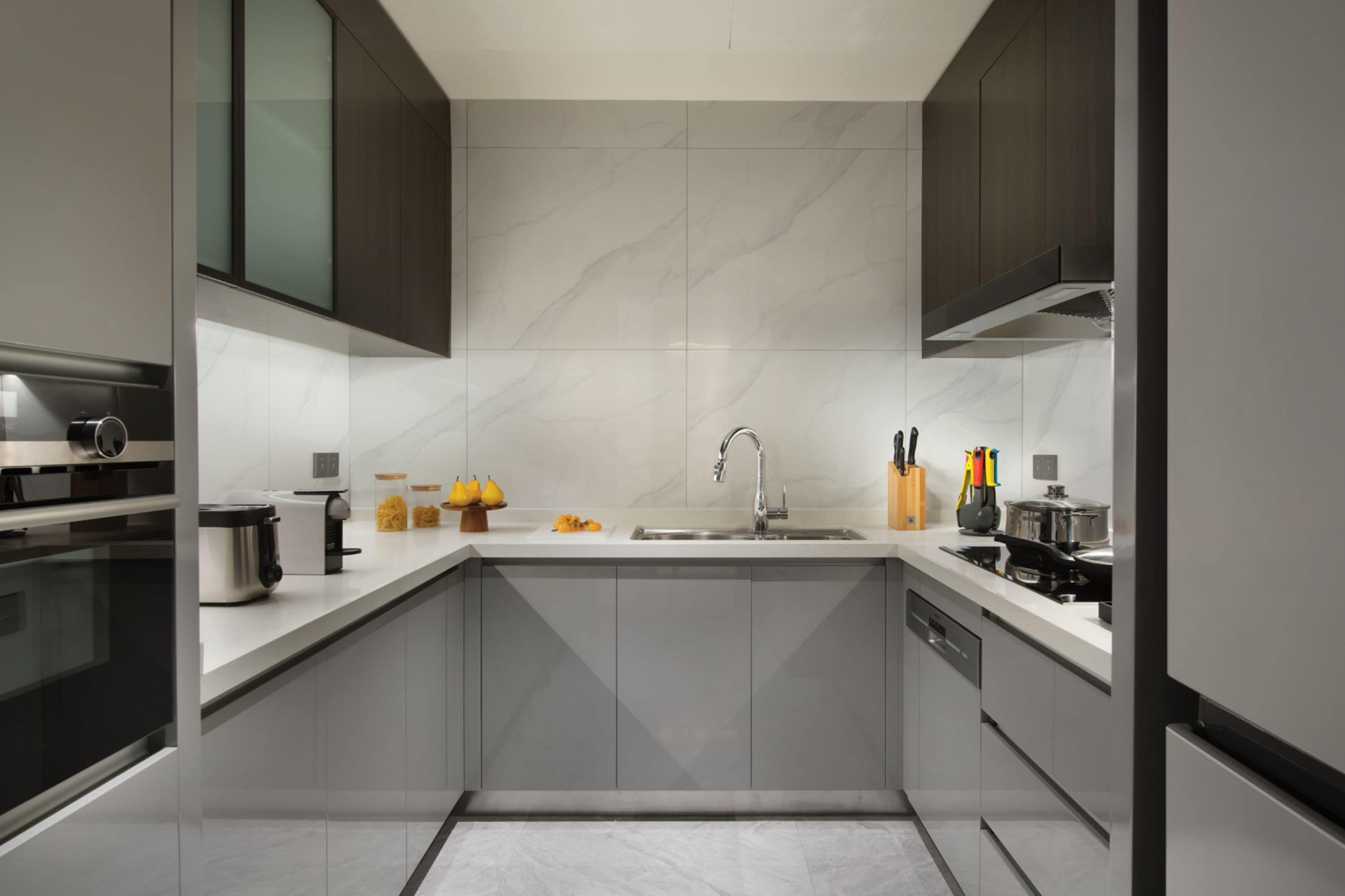 A modern kitchen with grey cabinets, a stainless steel sink, and a built-in oven.