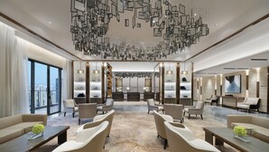A modern hotel lobby with a central seating area, a reception desk, and a large window offering a city view. - Oakwood Residence Foshan (Foshan)