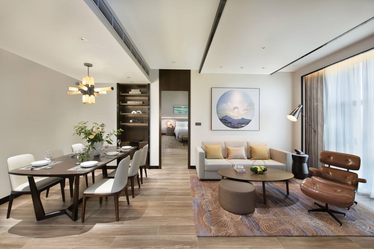 A modern hotel room with a dining area, a sofa, and a coffee table.