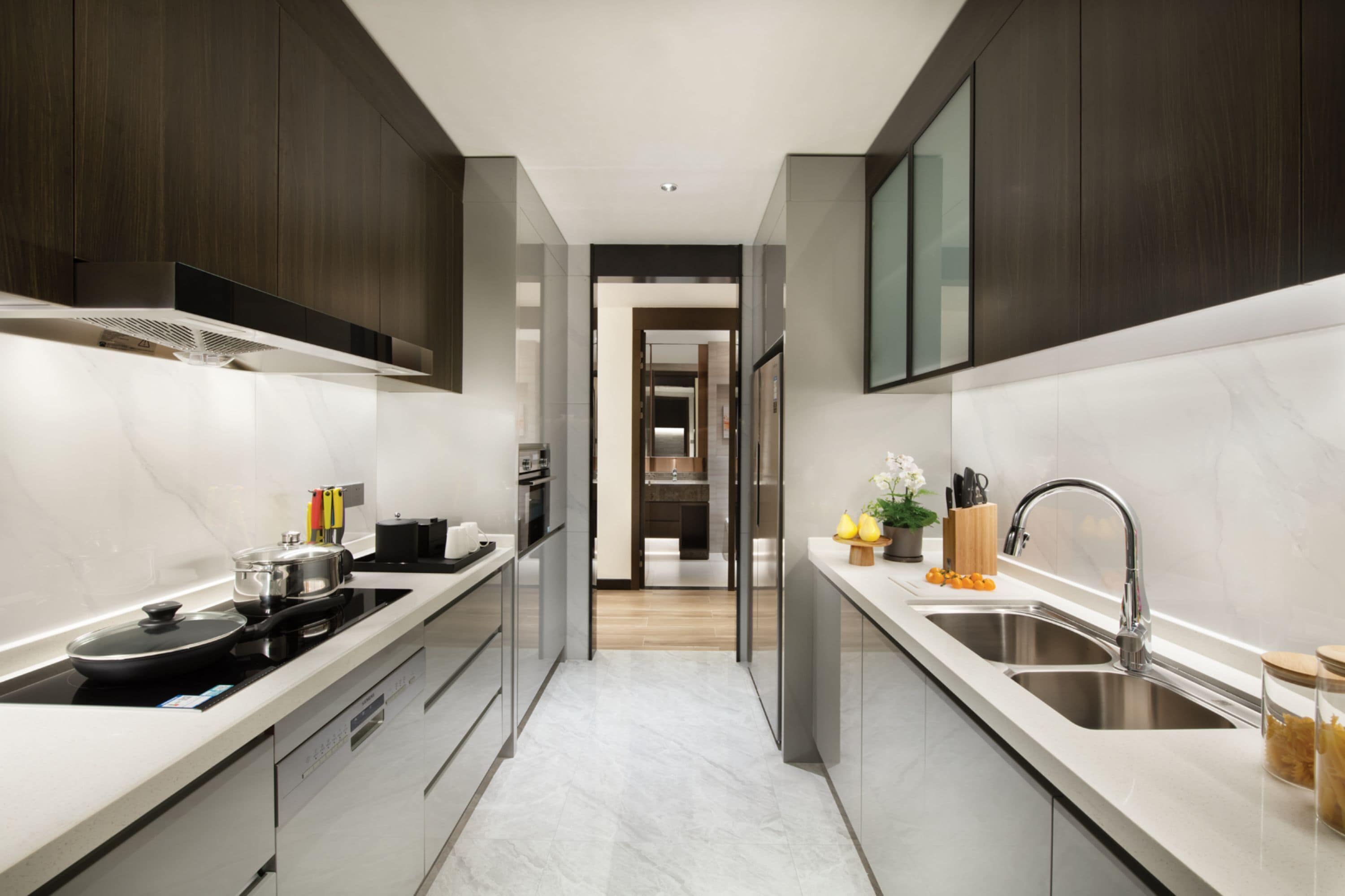 A modern kitchen with dark wood cabinets, a stainless steel sink, and a marble countertop.